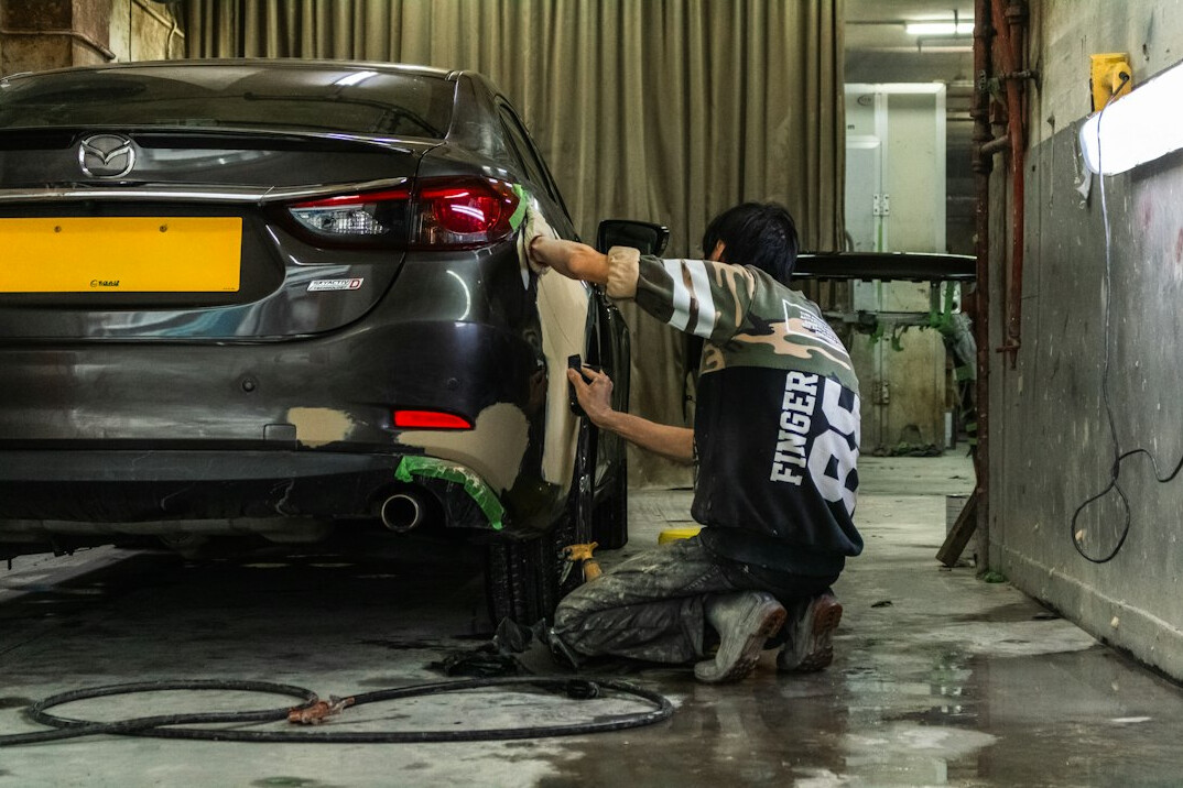 Car resting on a lift in a bright auto body workshop